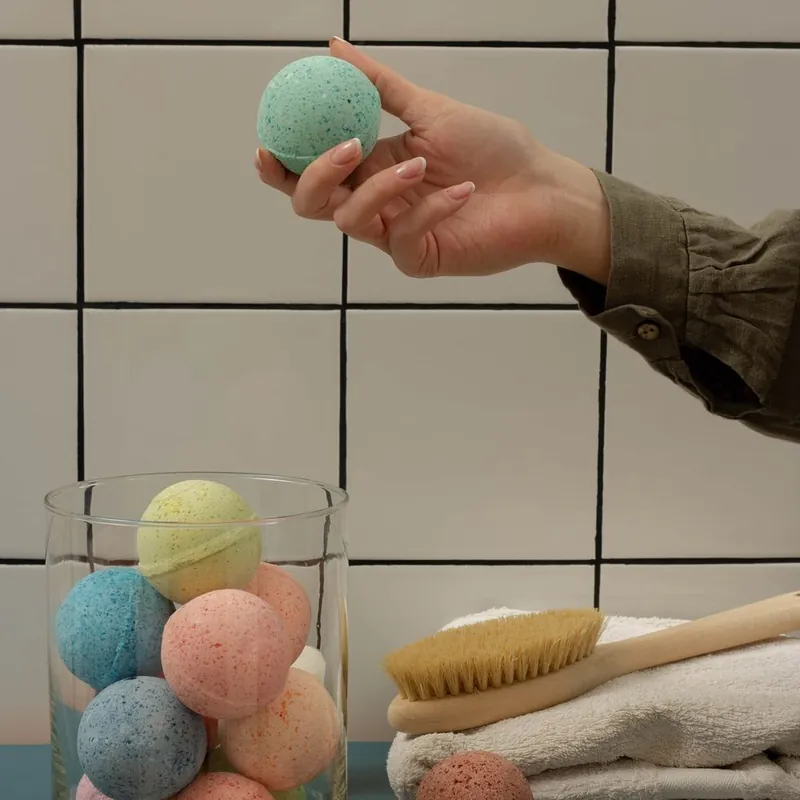 Colorful handmade bath bombs displayed in a jar with towels