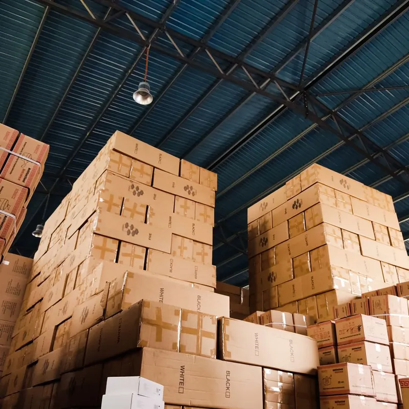 Warehouse of stacked cardboard boxes representing managed packaging inventory and cost
